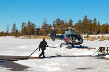 Sert kış havasında, karlı havada helikopter pistinde çalışan bir adam.