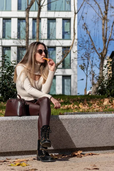 Mladá dívka v zimním oblečení jíst churros na vánočním trhu — Stock fotografie