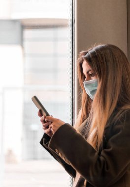 Genç bir kadın halka açık bir yerde akıllı telefonuyla konuşuyor.