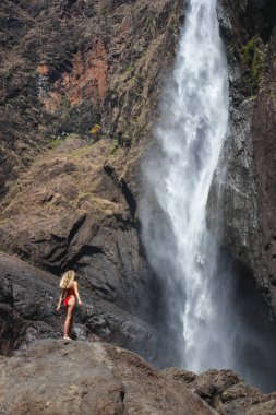 Sarışın kız Avustralya 'da büyük bir şelaleye bakıyor.