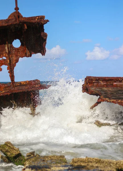 Meereswellen schlagen hart auf ein verrostetes gesunkenes Schiff, das im Sand Australiens gestrandet ist — Stockfoto