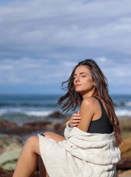 Young brunette woman feeling the sea breeze on her face and hair on the beach — Stock Photo, Image