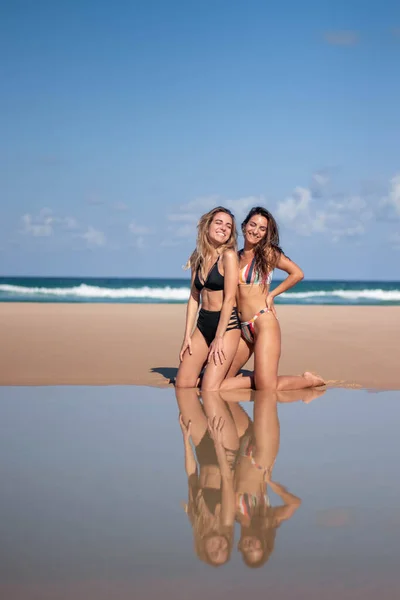 Dziewczyna w bikini śmieje się na plaży z odbiciem w wodzie — Zdjęcie stockowe