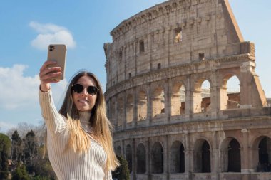 Roma, İtalya 'da kolezyumun önünde selfie çeken mutlu genç bir kadın.