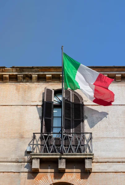 Italiens flagga viftar på en balkong i klassisk romersk byggnad med blå himmel — Stockfoto