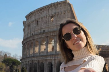 Genç sarışın kadın güneşli bir günde Roma Kolezyumu 'nda selfie çekiyor.