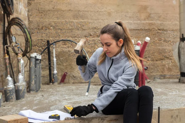 Jeune femme clouant avec un marteau dans le chantier de construction de sa maison — Photo