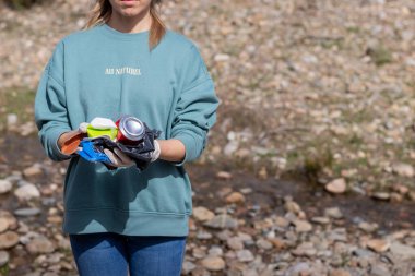 Nehrin önünde elinde doğadan gelen çöplerle tanınmayan bir kadın.