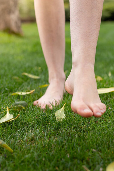 Bare legs and feet with goosebumps walking on the grass to connect with nature