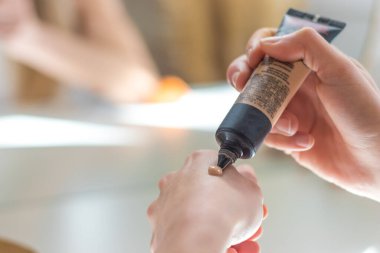 Makyaj yapmadan önce eline renk örneği olarak temel döken kadın.