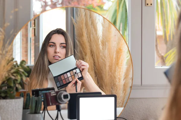 Женщина-блогер рекомендует палитру теней для век, показывающую ее любимые цвета — стоковое фото