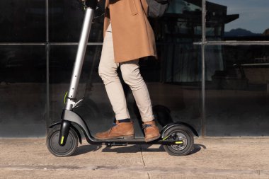 Alternatif ve çevre dostu ulaşım olarak şehrin finans bölgesinde elektrikli scooter kullanan bir adam görüntüsü