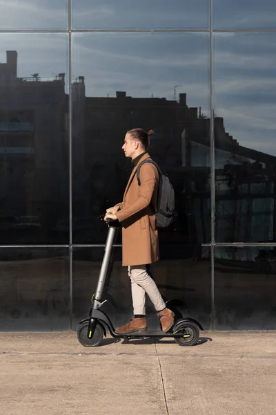 Şehir merkezinin finans bölgesinde elektrikli scooter kullanan genç bir işadamının dikey görüntüsü — Stok fotoğraf