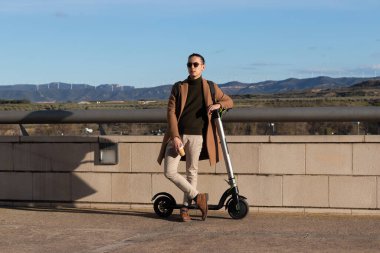 Çalışan genç işadamı, elektrikli scooter kullanarak sürdürülebilir ve sağlıklı bir yaşam tarzına ara veriyor.