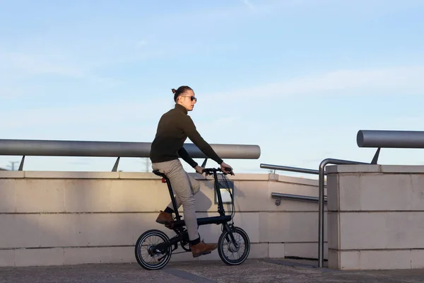 Entspannter junger Mann genießt eine Radtour durch die Stadt als Tourist, der neue Orte mit dem Elektrofahrrad sucht — Stockfoto