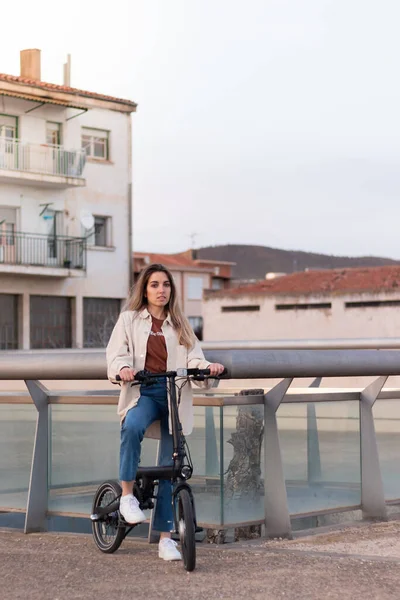 Frau blickt in Kamera, während sie mit dem Elektrofahrrad nach Hause in eine arme europäische Stadt mit Kopierraum fährt — Stockfoto