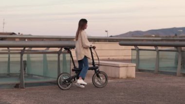 Young woman riding home and electric bike in the city at night time