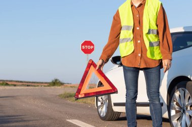 Elinde kırmızı üçgen tutan bir adam diğer yol kullanıcılarını arabasının kopyalama alanı ile ilgili sorunları olduğu konusunda uyardı.