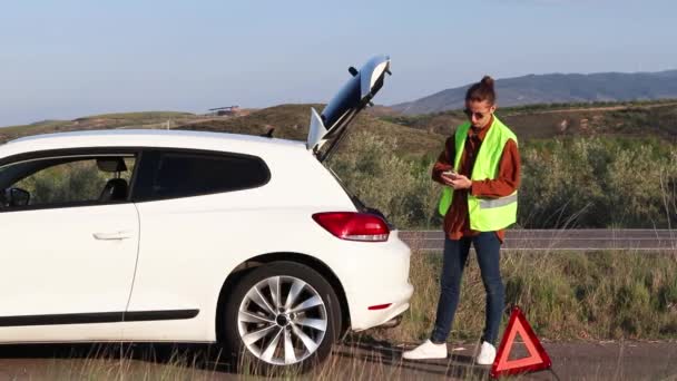 Young man on a vest calling roadside assistance to get the car a fix — Vídeo de stock