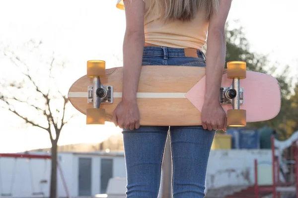 Neosobní close up portrét štíhlé mladé latinské dívky drží přírodní vintage skateboard za jejími zády — Stock fotografie