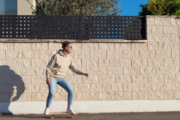 Mladý hipster muž na housce na skateboardu na sobě pouliční styl oblečení v odpoledních hodinách na jaře — Stock fotografie