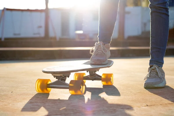 Krásné podsvícené fotografie křižníku skateboard v držení nohy mladé dívky v parku — Stock fotografie