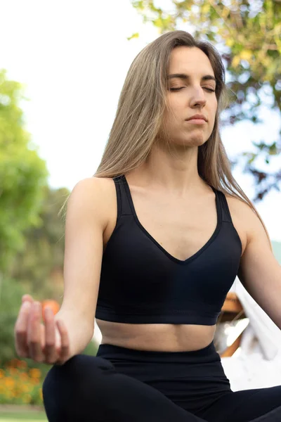 Vista vertical de la joven hermosa mujer rubia meditando en pose de loto en el aire libre, parque, jardín, bosque — Foto de Stock