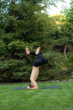 Bahçede başını paspasa dayayarak kendini dik duruma sokmaya çalışan genç adam.