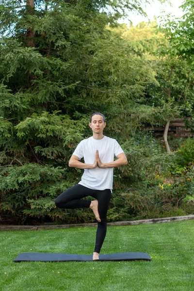 Joven yogui practicando yoga de pie en el ejercicio de Vrksasana, pose en el árbol, ejercitándose, usando ropa deportiva — Foto de Stock