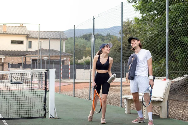 Compañeros de tenis caminando en una cancha de tenis con ropa de soprtswear casual riendo apenas mientras se divierten y buen tiempo — Foto de Stock