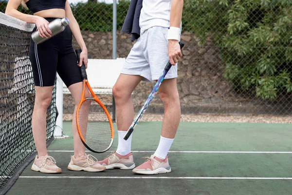 Side view of fit in shape young man and woman chatting after a tennis match relaxed closed to the net — Stockfoto