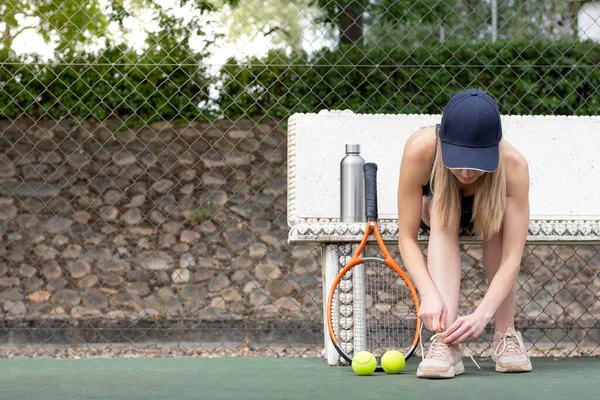 Sports woman getting ready and preparing for playing a game of tennis tying laces of her shoes outdoor — Stock Fotó