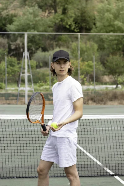 Siyah şapkalı genç bir tenisçinin ön portresi. C 'sine bakıyor ve yeşil kortta oynamak için bekliyor.. — Stok fotoğraf