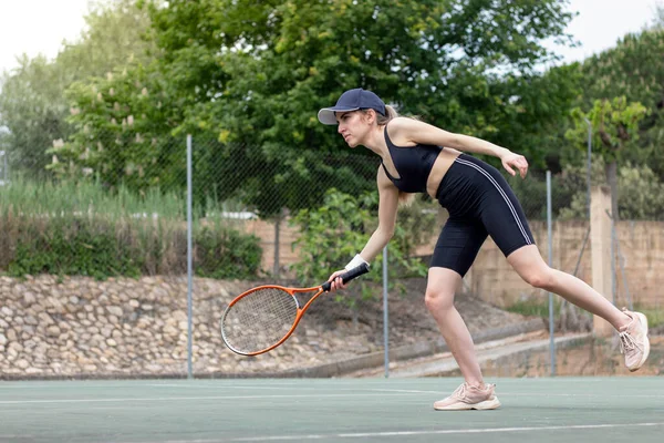 Mladá žena tenista na culíku se snaží trefit míč při tréninku na denní trénink zápas — Stock fotografie