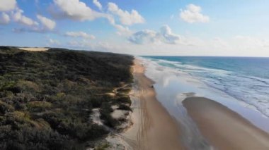 Yüksek açılı insansız hava aracı kuşları 4WD sürüşünü görür. Fraser Adası, Queensland, Avustralya 'daki sonsuz kumsalı fırlatır.