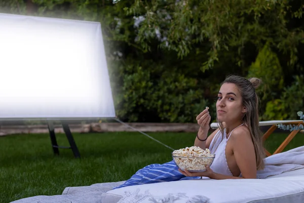 Młoda Kobieta Patrzy Kamery Oglądając Film Ogrodzie Pokazując Popcorn Jej — Zdjęcie stockowe