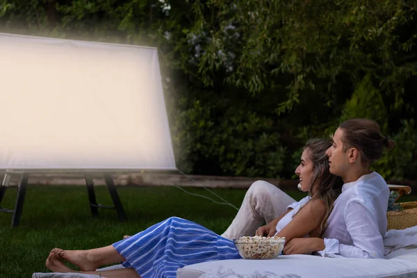 Young Cute Couple Embracing Sitting Garden Date Night Watching Movie — Zdjęcie stockowe