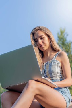 Bilgisayarında dijital göçebe olarak çalışan sarışın genç bir kadının düşük açılı görüntüsü.