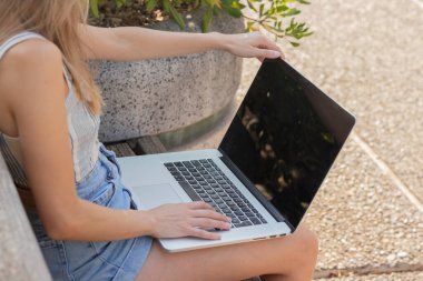 Yazın doğa havasının tadını çıkarmak için dışarıda dizüstü bilgisayar kullanan tanınmayan genç bir kadın.