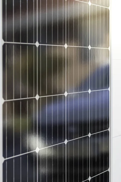 Super closeup view of monocrystalline black solar panel with a white car reflection on it. Renewable solar energy concept