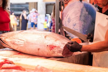 Freshly caught tuna being cut by unrecognizable fisherman at the store in the market with a knife