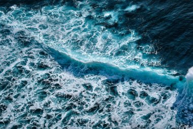 Okyanustaki su sıçrayan dalgaların hava görüntüsü. Mavi temiz dalgalı deniz suyu.