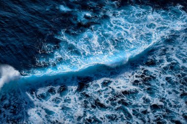 Okyanustaki su sıçrayan dalgaların hava görüntüsü. Mavi temiz dalgalı deniz suyu.