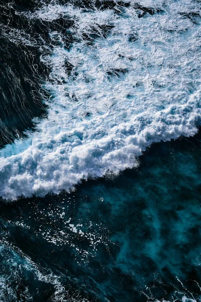 Okyanustaki su sıçrayan dalgaların hava görüntüsü. Mavi temiz dalgalı deniz suyu.