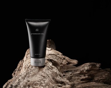 Black tubes with mens cosmetics after shave gel on wooden texture of driftwood, stump