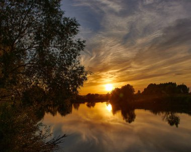 Beautiful sunset on the river bank. Sunset river landscape. River at sunset. Red sunset river