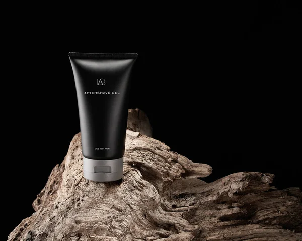 Black tubes with mens cosmetics after shave gel on wooden texture of driftwood, stump Stockfoto