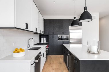 Şikago, IL, ABD - 8 Şubat 2020: Siyah ve beyaz dolapları, paslanmaz çelik Wolf ve Sub-Zero aletleri ve beyaz granit tezgahta oturan bar tabureleri olan modern bir mutfak.