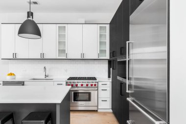 Şikago, IL, ABD - 8 Şubat 2020: Siyah ve beyaz dolapları, paslanmaz çelik Wolf ve Sub-Zero aletleri ve beyaz granit tezgahta oturan bar tabureleri olan modern bir mutfak.