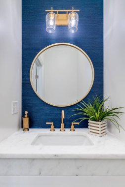 Chicago, IL, ABD - 7 Haziran 2020: Mavi duvar kağıdı, altın donanım ve beyaz mermer tezgahlı küçük bir banyo.